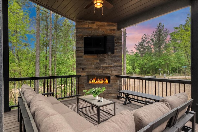 deck featuring an outdoor living space with a fireplace and ceiling fan