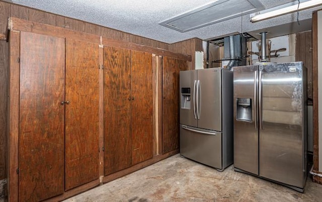 kitchen with stainless steel fridge, a textured ceiling, and wooden walls