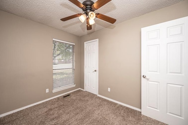 unfurnished bedroom with carpet flooring, ceiling fan, and a textured ceiling