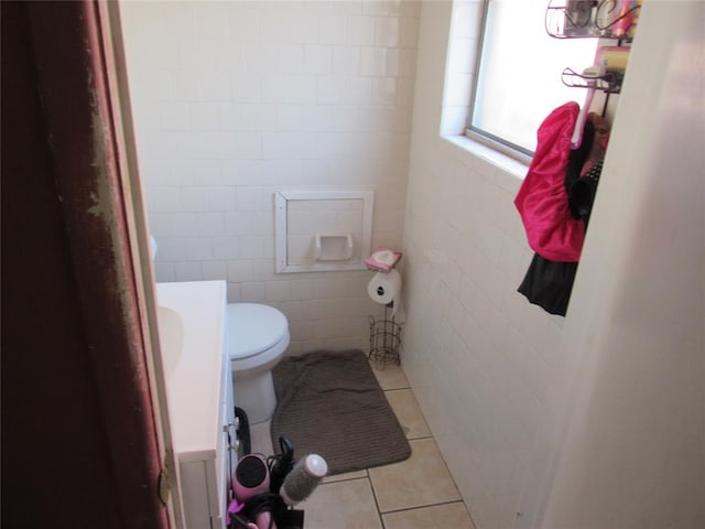 bathroom featuring tile patterned flooring, tile walls, and toilet