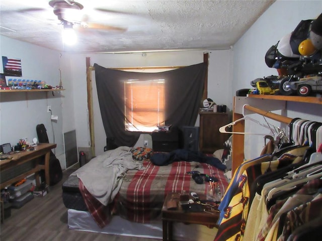 bedroom with ceiling fan, wood-type flooring, and a textured ceiling