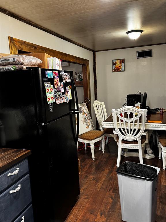 kitchen featuring black refrigerator, ornamental molding, and dark hardwood / wood-style floors