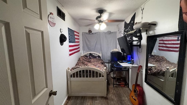 bedroom with a textured ceiling, dark hardwood / wood-style floors, and ceiling fan