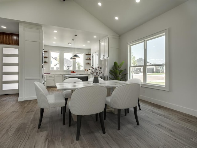 dining area with high vaulted ceiling and light hardwood / wood-style flooring