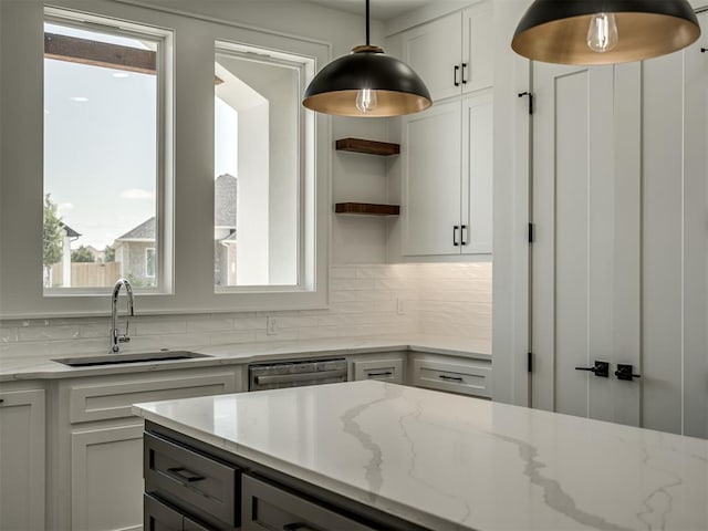 kitchen featuring sink, white cabinetry, decorative light fixtures, dishwasher, and light stone countertops