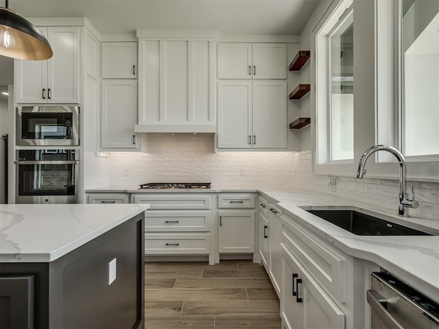 kitchen featuring white cabinetry, appliances with stainless steel finishes, light stone countertops, and sink