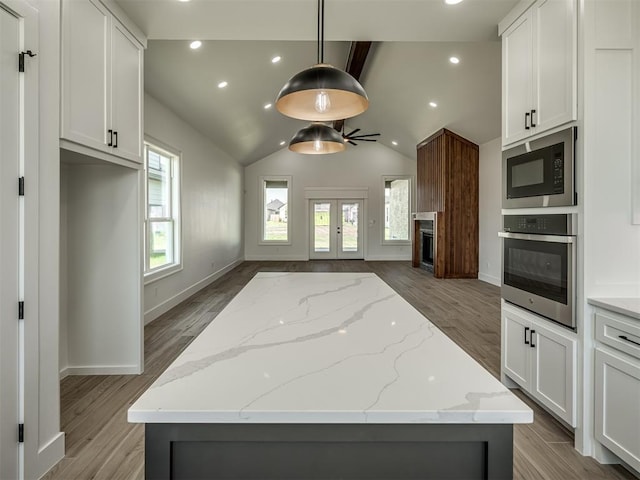 kitchen with light stone countertops, oven, and white cabinets