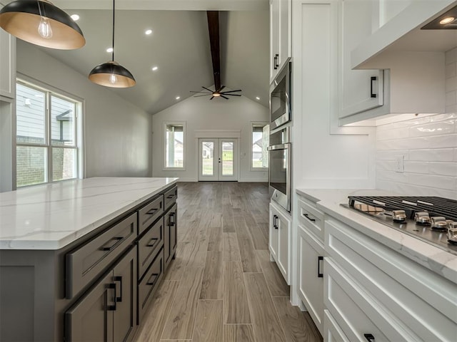 kitchen with light stone counters, decorative light fixtures, white cabinets, and appliances with stainless steel finishes