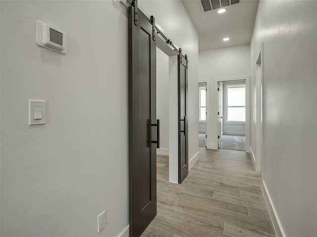 hallway featuring a barn door and light wood-type flooring