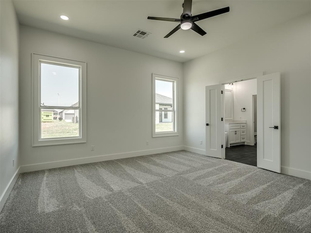 unfurnished bedroom featuring connected bathroom and dark colored carpet