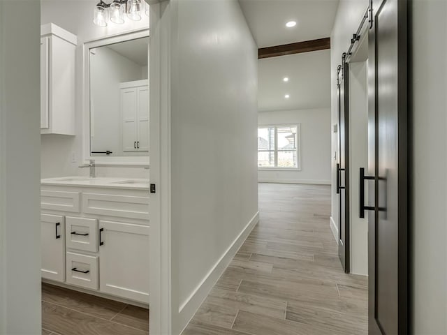 hall with sink, a barn door, and light wood-type flooring