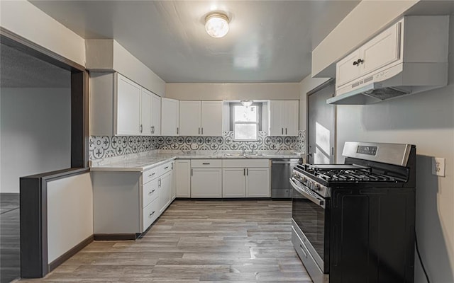 kitchen featuring backsplash, white cabinets, sink, light wood-type flooring, and appliances with stainless steel finishes