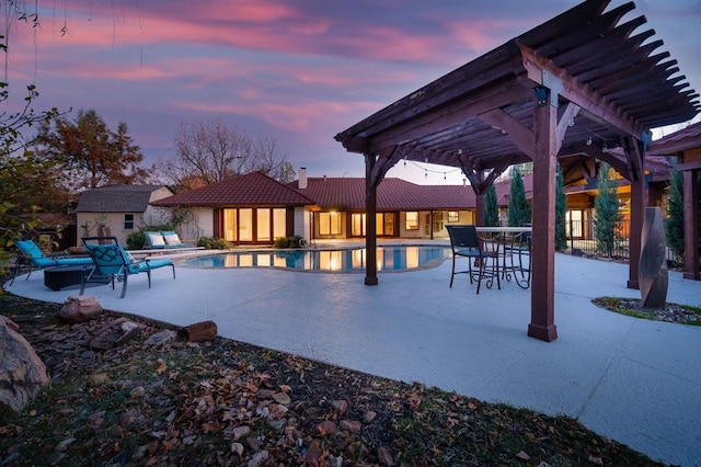 pool at dusk with a pergola, a shed, and a patio area