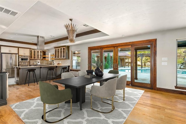 dining area featuring crown molding, light hardwood / wood-style flooring, a tray ceiling, and a wealth of natural light