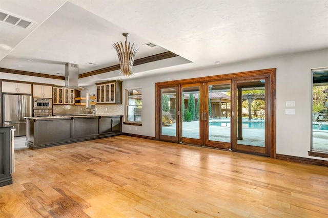 interior space featuring island range hood, light wood-type flooring, a healthy amount of sunlight, and stainless steel refrigerator