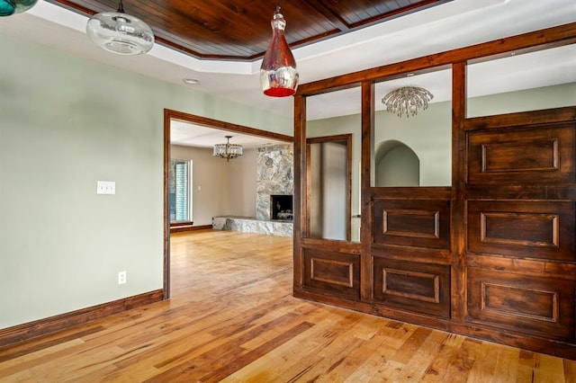 unfurnished room with a fireplace, light hardwood / wood-style floors, and wooden ceiling