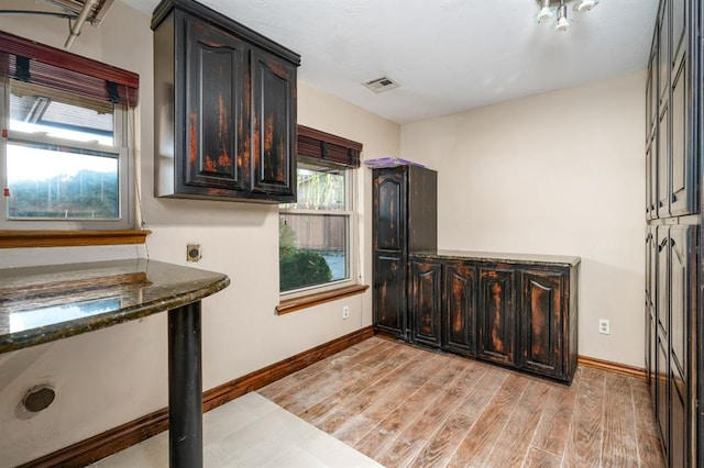 kitchen with dark brown cabinetry and dark stone counters