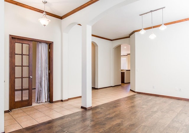 foyer entrance featuring ornamental molding, arched walkways, baseboards, and wood finished floors