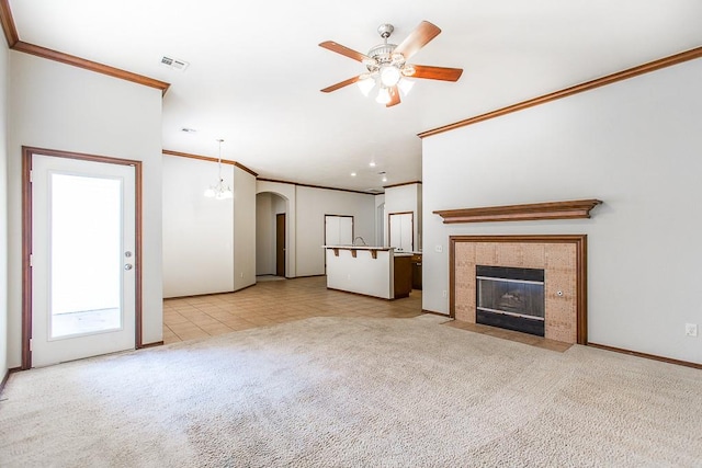 unfurnished living room with a fireplace, light carpet, ceiling fan with notable chandelier, and ornamental molding