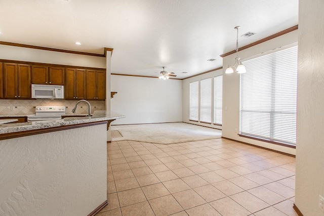 kitchen with light tile patterned flooring, ceiling fan with notable chandelier, pendant lighting, and white appliances