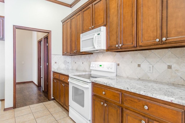 kitchen with light stone countertops, ornamental molding, white appliances, and light wood-type flooring