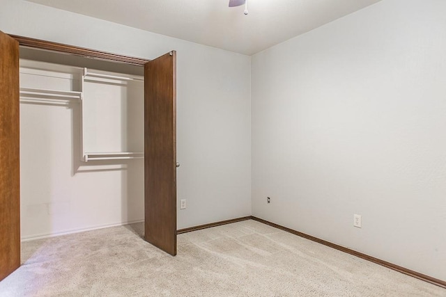 unfurnished bedroom featuring a closet, light colored carpet, and ceiling fan