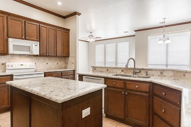 kitchen with crown molding, tasteful backsplash, a kitchen island, a sink, and white appliances