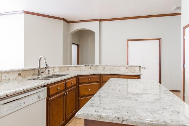 kitchen featuring white dishwasher, a sink, visible vents, light stone countertops, and brown cabinetry