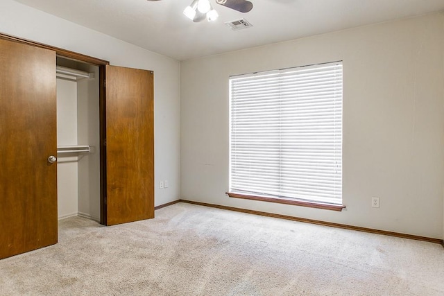 unfurnished bedroom with carpet floors, multiple windows, visible vents, and a ceiling fan