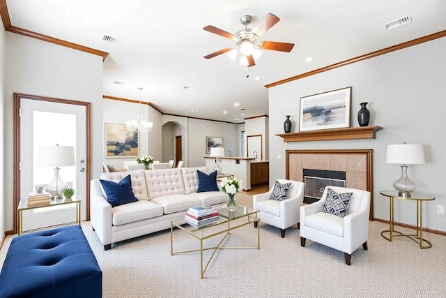 carpeted living room featuring baseboards, visible vents, crown molding, a fireplace, and ceiling fan with notable chandelier