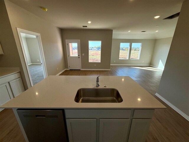 kitchen with dark hardwood / wood-style flooring, dishwasher, an island with sink, and plenty of natural light