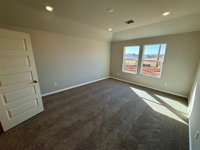 empty room featuring dark carpet and lofted ceiling