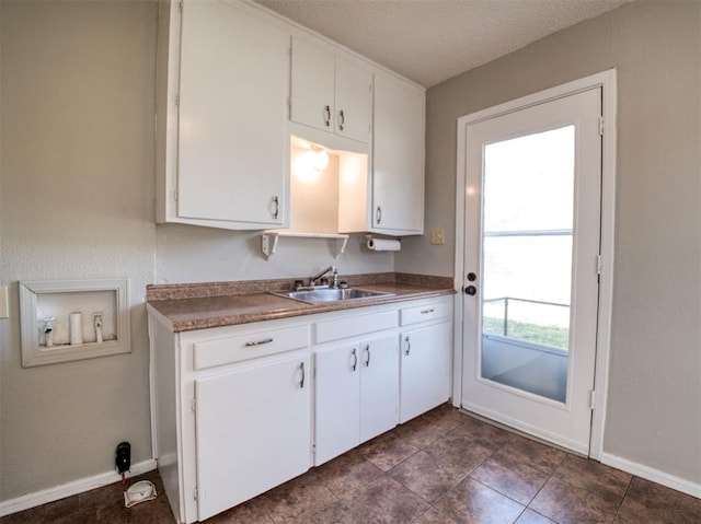 kitchen featuring a textured ceiling, dark tile patterned floors, white cabinetry, and sink