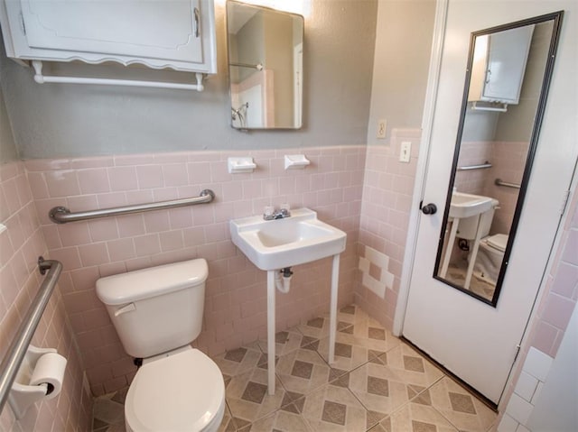 bathroom with sink, toilet, and tile walls