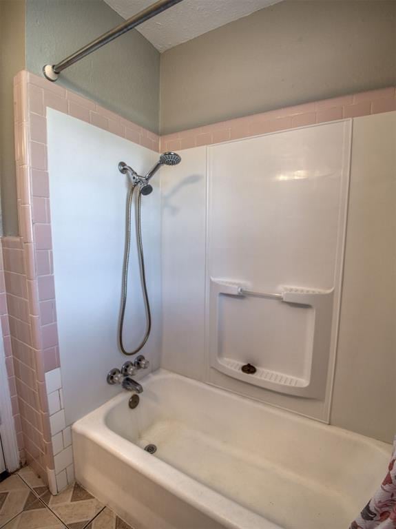 bathroom with tile patterned flooring, a textured ceiling, and bathing tub / shower combination