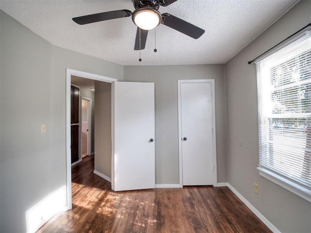 unfurnished bedroom with multiple windows, ceiling fan, dark hardwood / wood-style flooring, and a textured ceiling