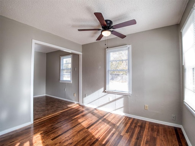 spare room featuring a textured ceiling, ceiling fan, a healthy amount of sunlight, and dark wood-type flooring