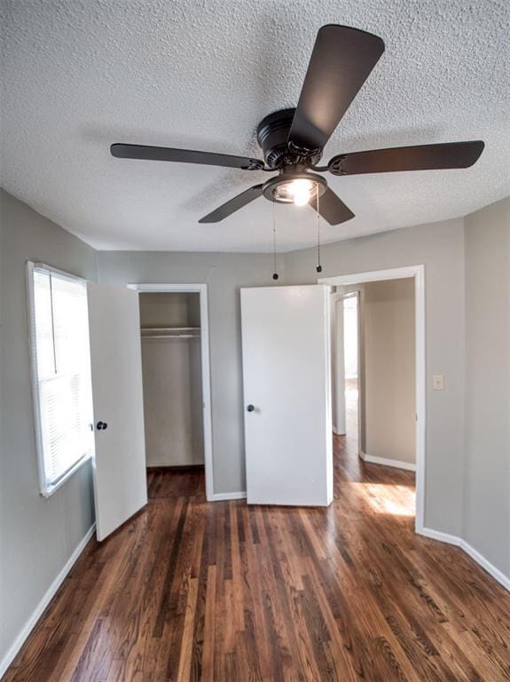 unfurnished bedroom featuring ceiling fan, a closet, dark wood-type flooring, and a textured ceiling