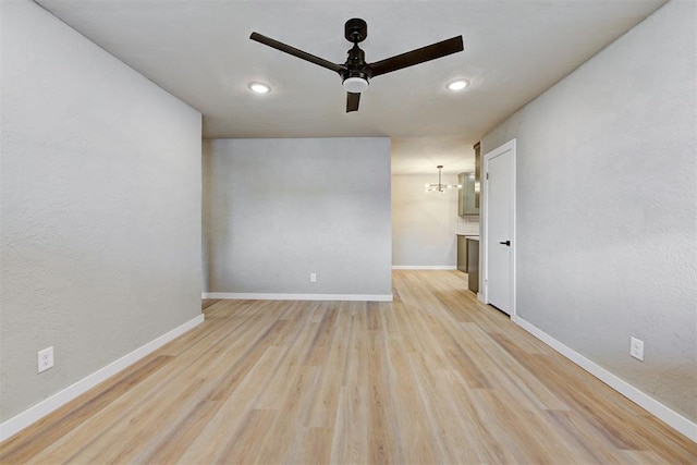 unfurnished room with ceiling fan with notable chandelier and light hardwood / wood-style floors