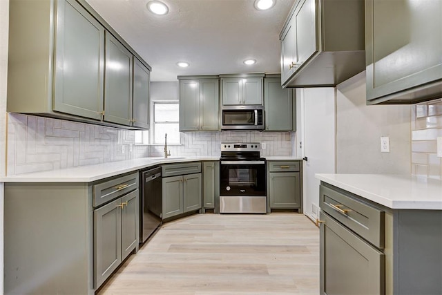 kitchen with backsplash, sink, light hardwood / wood-style flooring, and appliances with stainless steel finishes