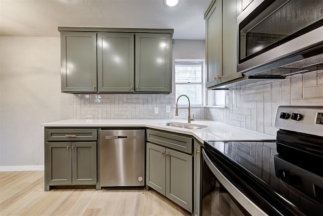 kitchen featuring light wood-type flooring, sink, appliances with stainless steel finishes, and tasteful backsplash