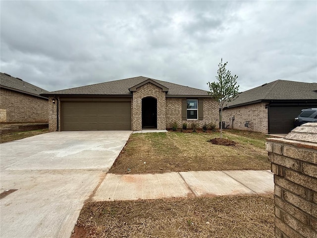 single story home featuring brick siding, an attached garage, a front yard, and concrete driveway