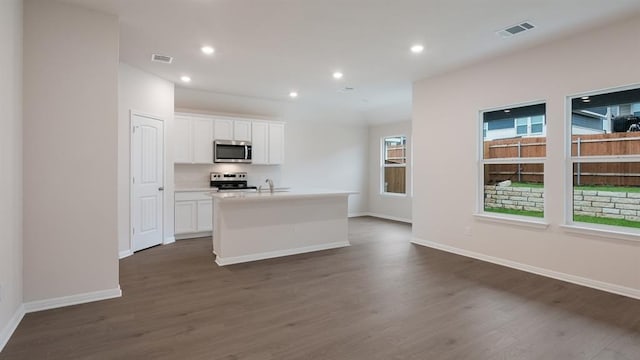 kitchen featuring visible vents, white cabinets, stainless steel appliances, and an island with sink