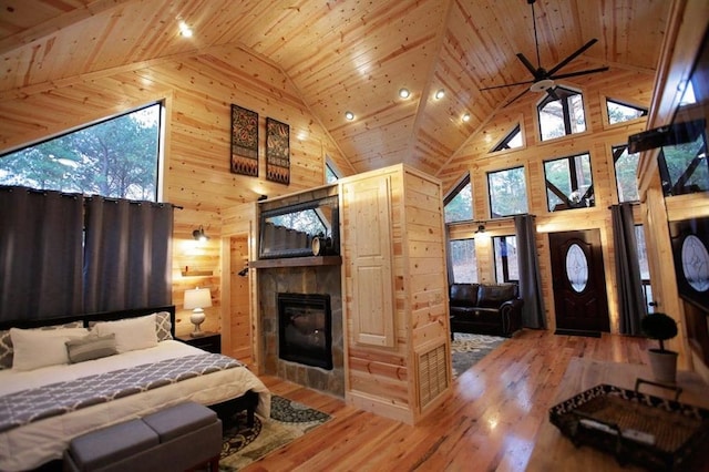 bedroom featuring high vaulted ceiling, wooden walls, a fireplace, wood-type flooring, and wood ceiling