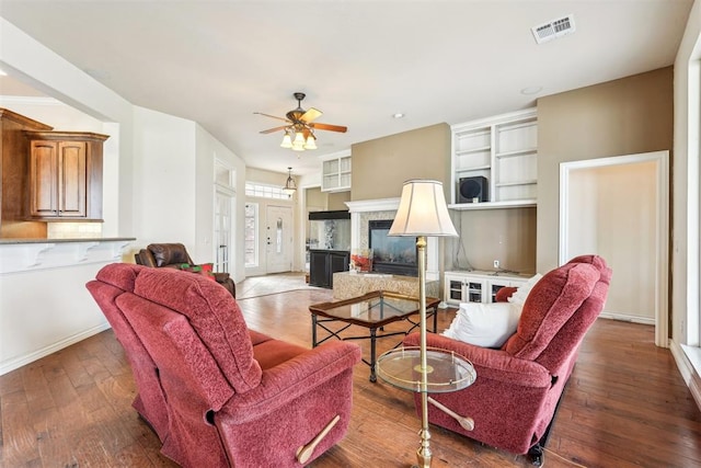 living room with a premium fireplace, hardwood / wood-style floors, and ceiling fan