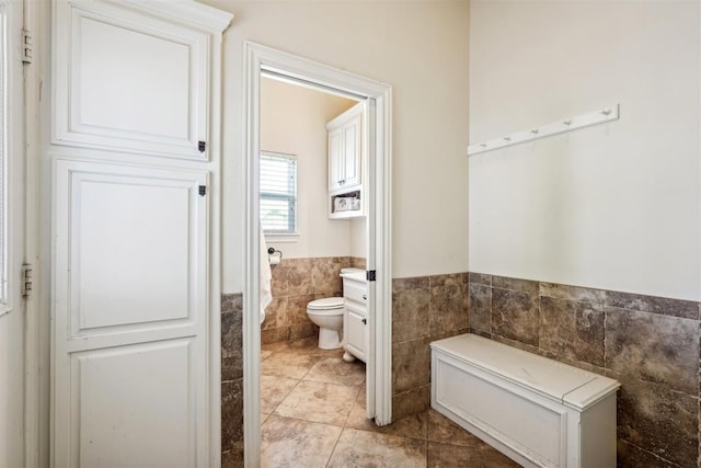 bathroom with tile patterned flooring, toilet, and tile walls