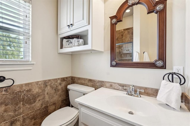 bathroom featuring vanity, tile walls, and toilet