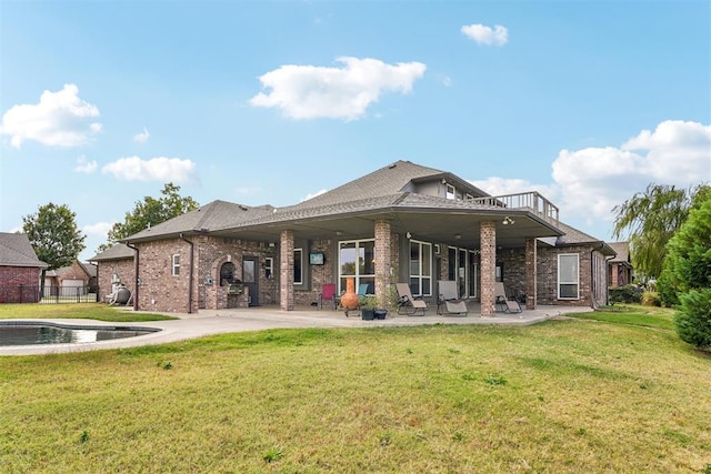 back of property with a yard, a balcony, and a patio