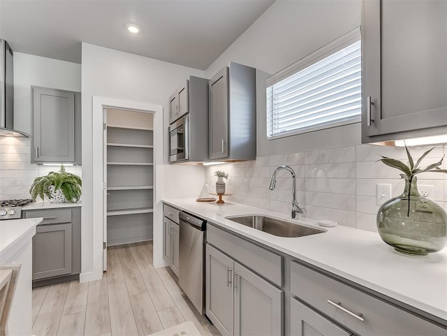 kitchen with gray cabinetry, sink, and stainless steel appliances