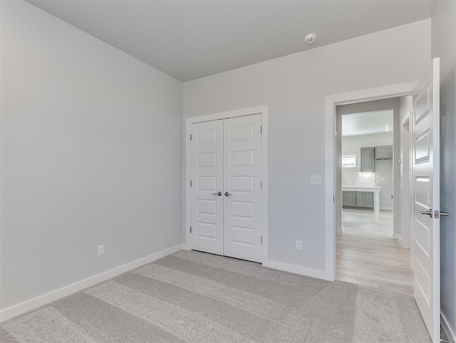 unfurnished bedroom featuring light carpet and a closet